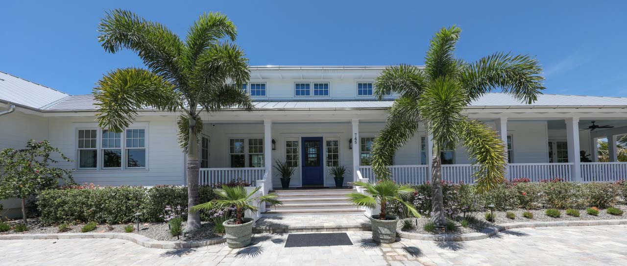 Very wide residential home with two palm trees in the front, located in Boca Grande